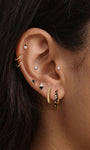 Trendy multi-piercing ear stacking look with KOSINER Puzzle black enamel leopard print sterling silver hoop earring, matched tiny cz studs, geometric triangle studs, textured gold hoops, chic edgy everyday ear styling