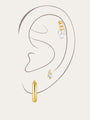 Collection of gold sterling silver earrings with cubic zirconia, including hoops and studs, styled on an ear.