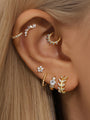 Gold plated sterling silver ear piercings featuring leaf, moon, flower and hoop styles adorned with cubic zirconia.