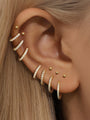 Model wearing gold dainty huggie hoop earrings and small studs with cubic zirconia on ear, showcasing styling and scale.