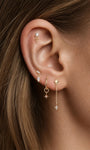 Close‑up layered curated ear look featuring 14K solid gold double marquise CZ drop flat back stud, helix and lobe piercings