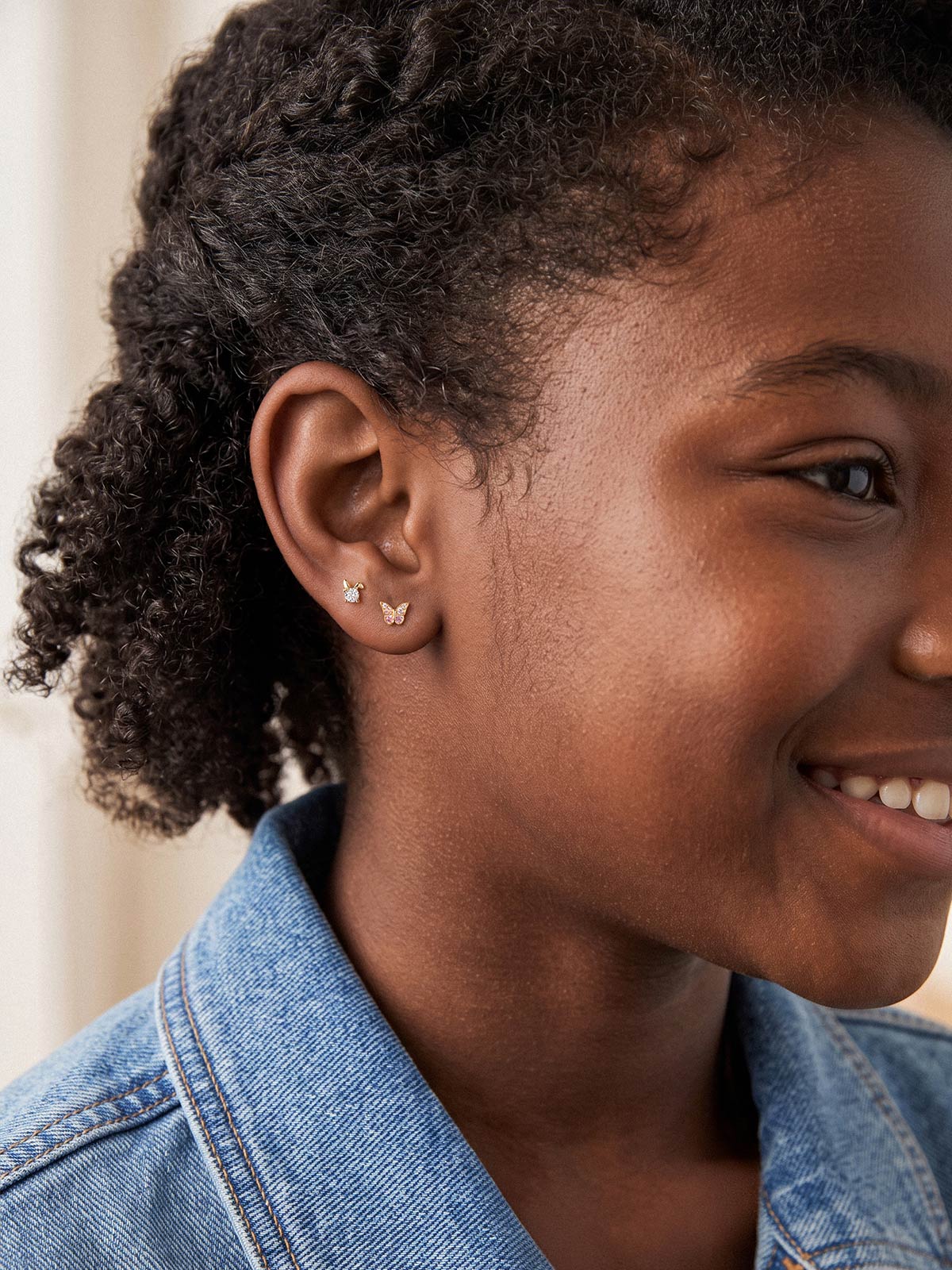 Model wearing a 14K gold butterfly stud with coordinating flat back earrings