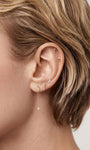 Short blonde hair curated ear look featuring gold kite cut CZ chain charm on lobe hoop, multiple helix piercings lifestyle shot