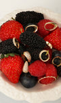 Stylized lifestyle flat lay featuring KOSINER ribbed ridge mini hoop mixed with assorted gold cartilage piercing jewelry arranged on fresh berries including strawberries, mulberries and blueberries in white ceramic bowl