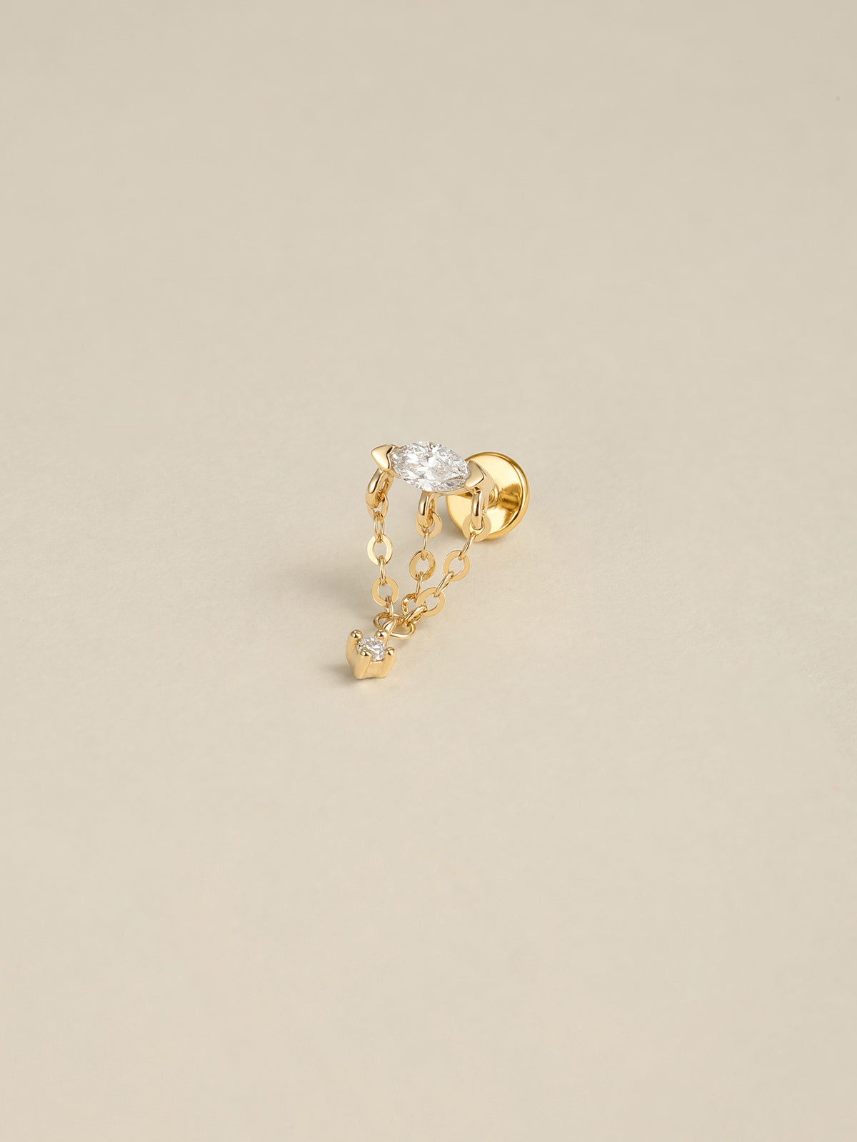 Angled still‑life shot of 14K solid gold multi‑chain tassel CZ dangle flat back labret stud on soft beige background