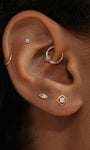 Close-up ear stack display with KOSINER Étoile radiant marquise CZ flat back stud paired with hollow square piercing stud and turquoise detail clicker hoop, delicate vintage-inspired cartilage piercing combination