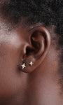 Close-up ear shot displaying two sizes of KOSINER Starlight octagonal star flat back studs set on ear lobe piercings, showcasing versatile minimalist wear on deep skin tone
