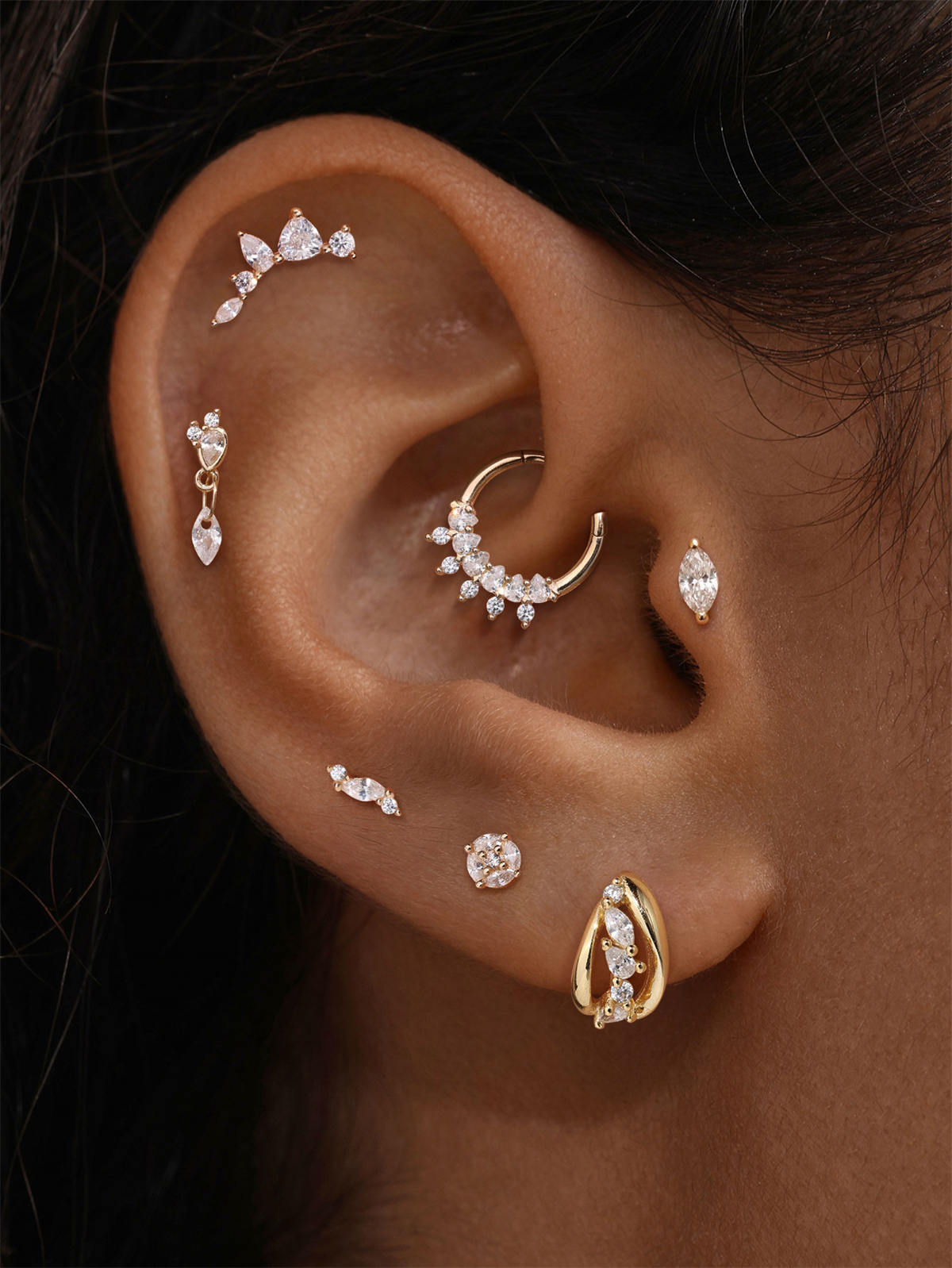 Close-up of ear stacked with dainty KOSINER pear cluster cz clicker hoops and studs, elegant multi-ear piercing aesthetic