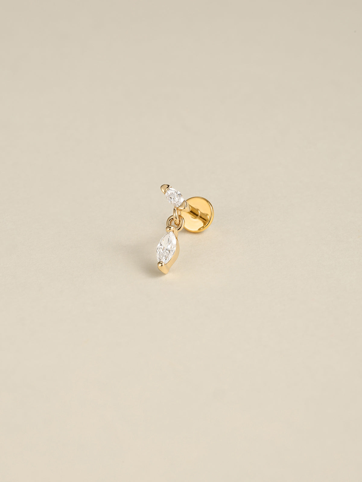 Angled still‑life shot of 14K solid gold double marquise CZ dangle flat back labret stud on soft beige background