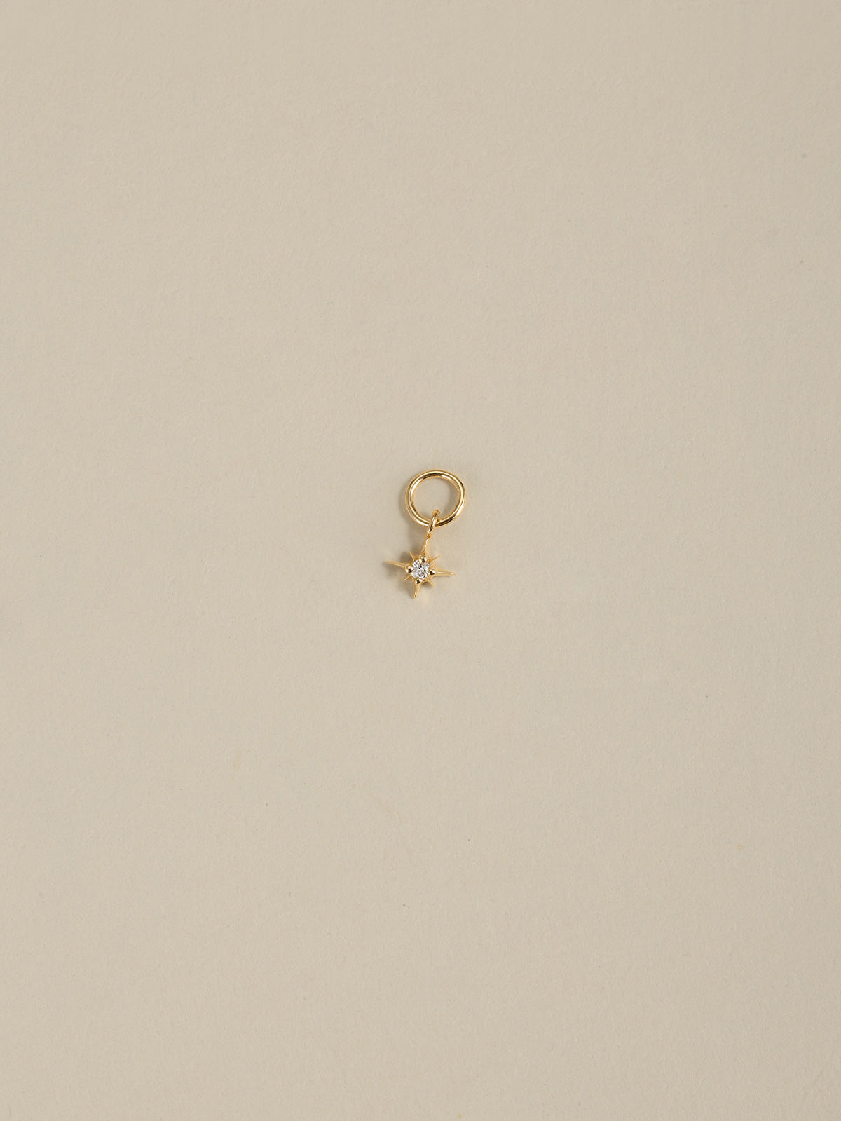 14K solid gold eight-point north star dangle charm with cubic zirconia, KOSINER detachable piercing ear charm on neutral beige background