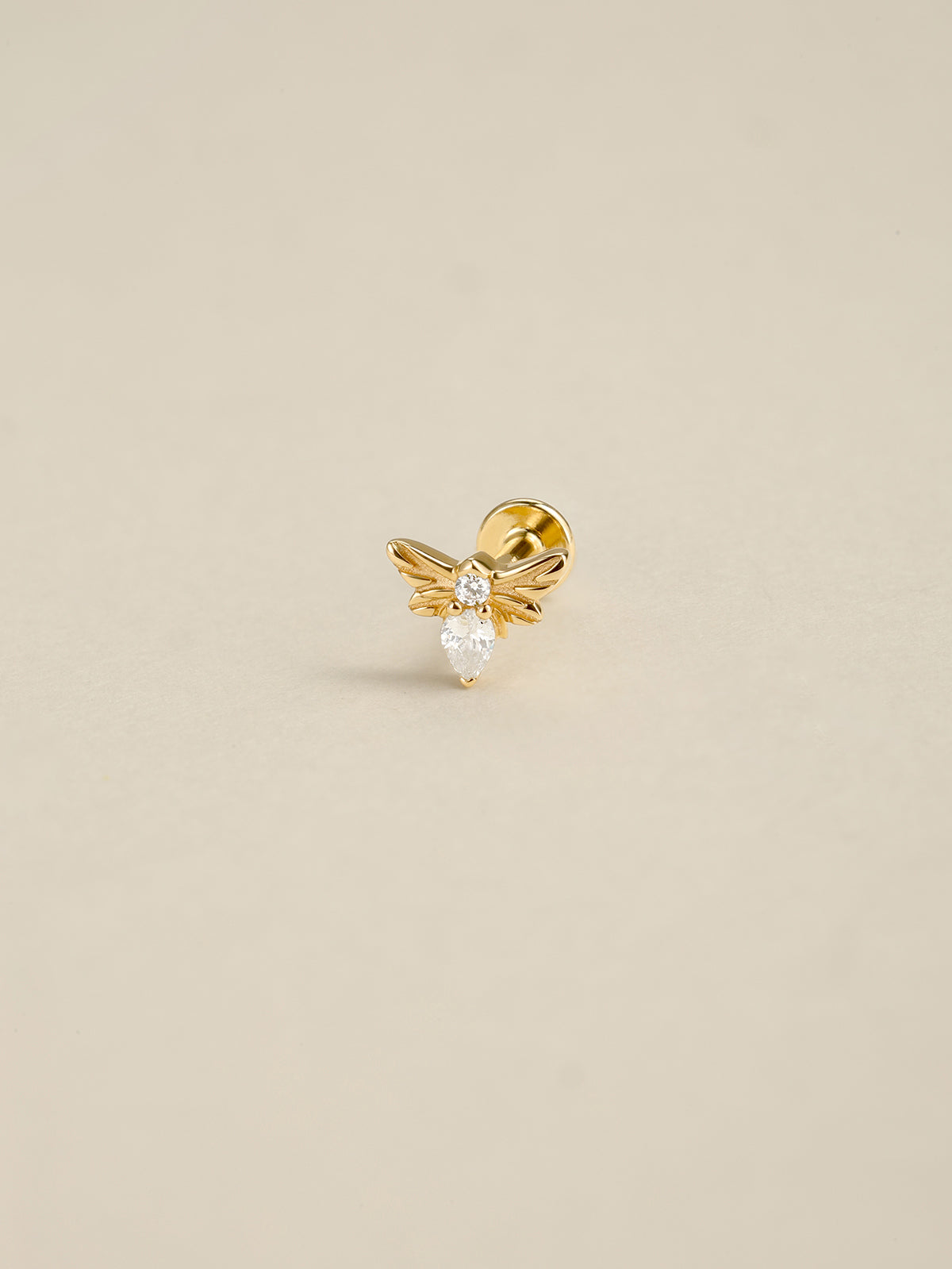 14K solid gold tiny bee flat back stud earring, pear cut cubic zirconia dainty bee cartilage piercing jewelry, close-up front view on neutral beige background