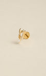 Angled still life shot of 14K solid gold battle axe drop flat back labret stud, clear marquise CZ dangle piercing jewelry on soft beige background