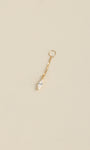 Angled still life shot of 14K solid gold kite drop chain charm, faceted kite CZ pendant on soft neutral beige background
