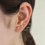 Three 18k gold plated 925 sterling silver floral stud earrings with cubic zirconia, shown on an ear.