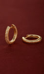 Pair of KOSINER Essentials 925 sterling silver gold-plated ridge textured clicker hoop earrings, ribbed corrugated surface detail, internal stamp marking, shot on soft burgundy suede fabric background
