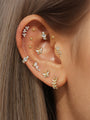Gold plated sterling silver ear piercings featuring dainty butterfly and flower studs with cubic zirconia, styled on ear.