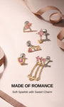 KOSINER Made of Romance pink gem piercing jewelry collection laid out with silky ribbon, including the signature Pink Ritual cross drop flat back stud, presenting a sweet sparkling romantic jewelry lineup