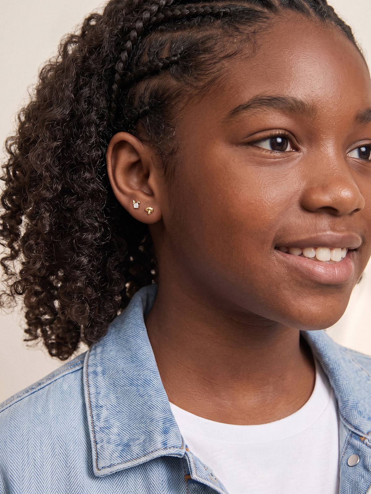 Model in a denim jacket wearing KOSINER Little Wonder gold mushroom and bunny studs in her lobe piercings