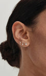 Close-up of human earlobe styled with KOSINER Seaspritz wine glass flat back stud, paired with seashell and other ocean-themed tiny studs, delicate minimalist daily ear stacking design