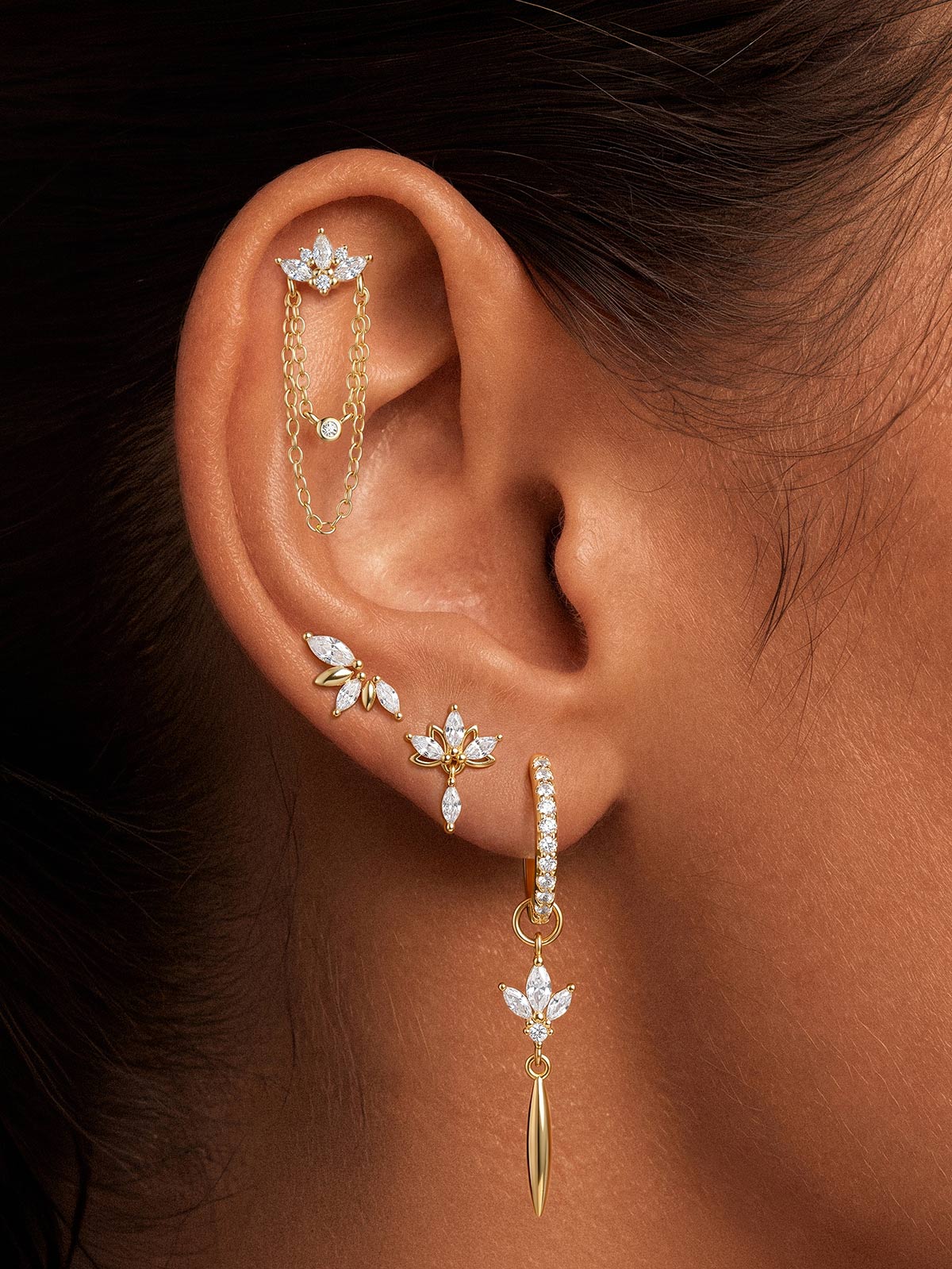 Model wearing KOSINER gold lotus tassel drop hoop in a curated ear stack