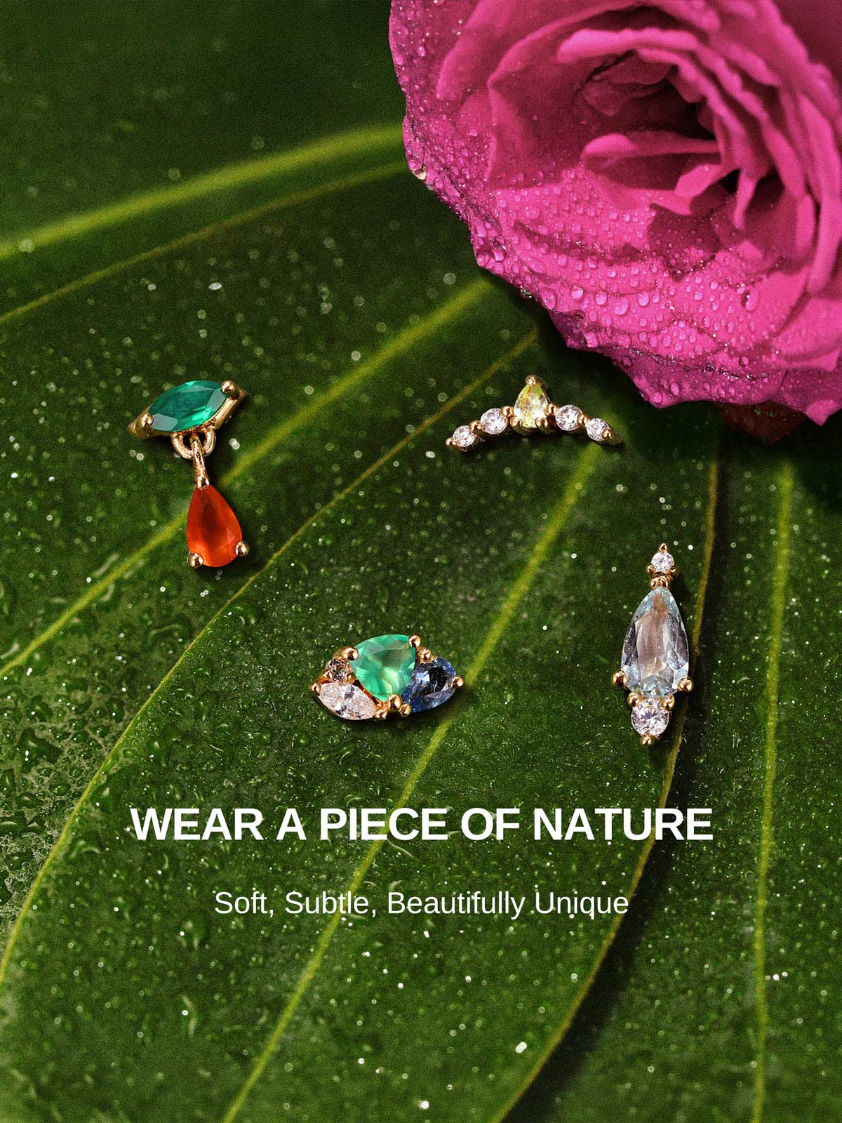 KOSINER Gem Garden nature-inspired colorful gem piercing studs laid on dewy green leaves and magenta rose, featuring pear blue topaz, emerald-orange dangle, crown, multi-shape cluster flat back styles
