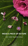 KOSINER Gem Garden nature-inspired purple gem piercing studs laid on dewy green leaves and magenta rose, featuring pear-marquise dangle, crown, three-stone, twisted square multi-shape designs