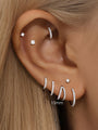Model's ear styled with multiple 16g titanium CZ hoop earrings and studs, showing 10mm hoop size options.