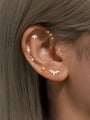 Gold sterling silver ear piercings with cubic zirconia, styled on ear. Square stud, starburst, lotus designs.
