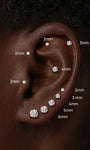 Curated full ear styling showcasing KOSINER round lab-grown diamond flat back studs ranging 2mm–6mm, placed across tragus, helix and earlobe piercings for visual size comparison