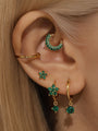 Gold-plated 925 sterling silver daith earring with green cubic zirconia garland design, styled with star earrings.