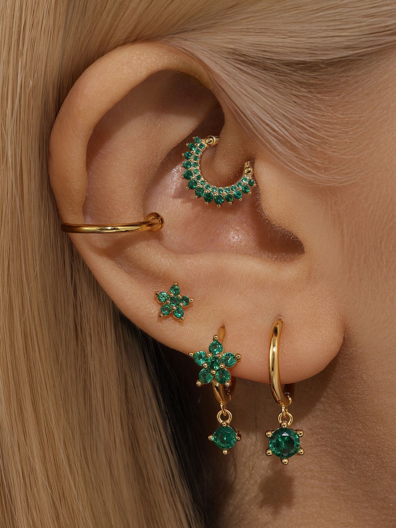 Gold-plated 925 sterling silver daith earring with green cubic zirconia garland design, styled with star earrings.