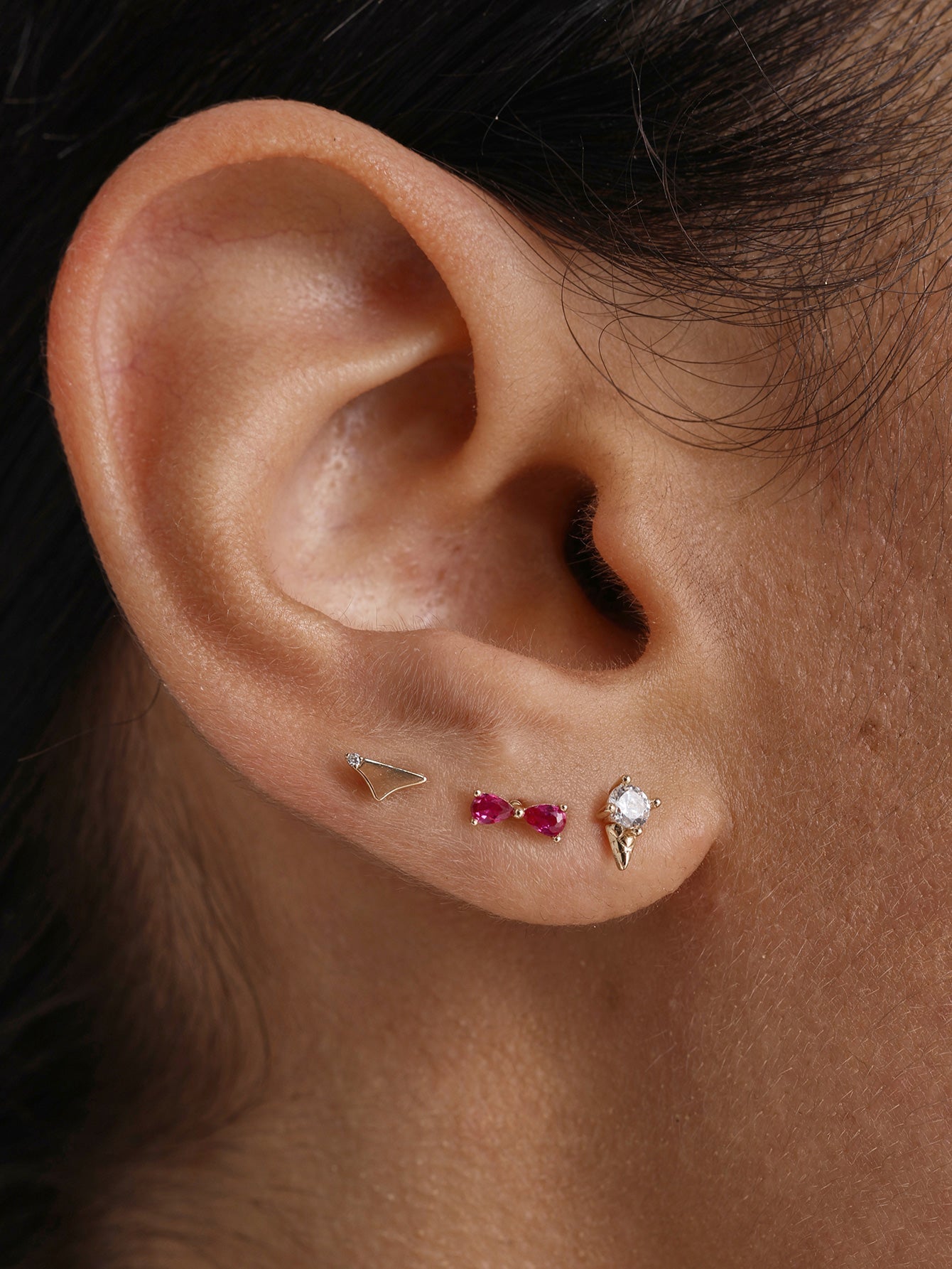 Close-up shot of human earlobe styled with KOSINER Seaspritz two-piece bikini flat back studs plus matching coordinating piercing stud, neat minimalist multi-hole ear stacking for daily summer wear