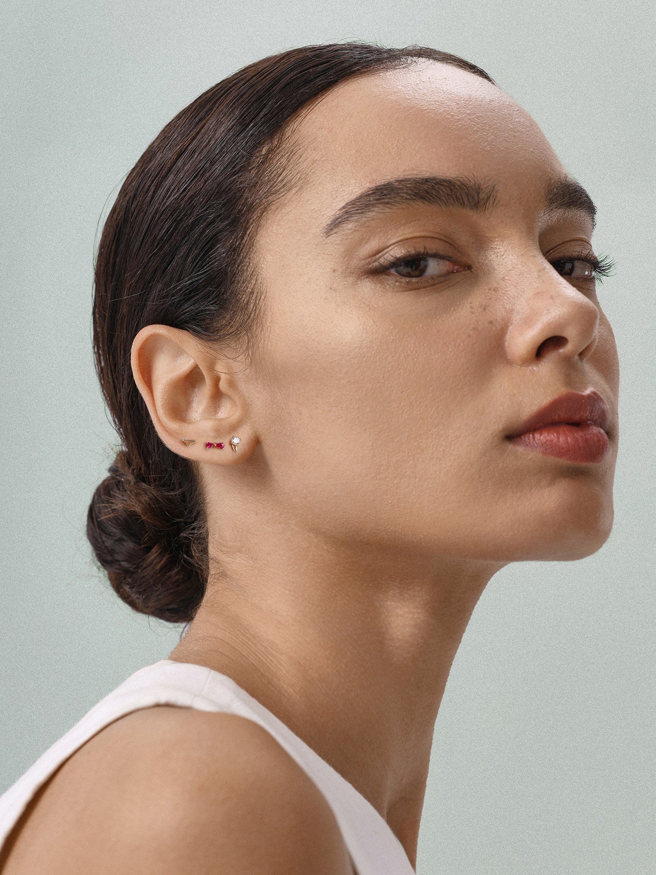 Elegant everyday styling with KOSINER Seaspritz tiny ice cream flat back stud on earlobe, model with neat low bun and plain neutral top, soft neutral background showcasing petite wearable seasonal piercing jewelry