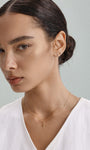 Elegant everyday styling with KOSINER Seaspritz tiny seahorse flat back stud on earlobe, model with neat low bun and plain neutral top, soft background showcasing petite wearable marine piercing jewelry