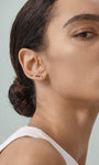 Daily minimalist styling with KOSINER Seaspritz bikini flat back studs on earlobe, model with sleek low bun and plain tank top, soft neutral background showing the delicate wearable design of vacation piercing jewelry