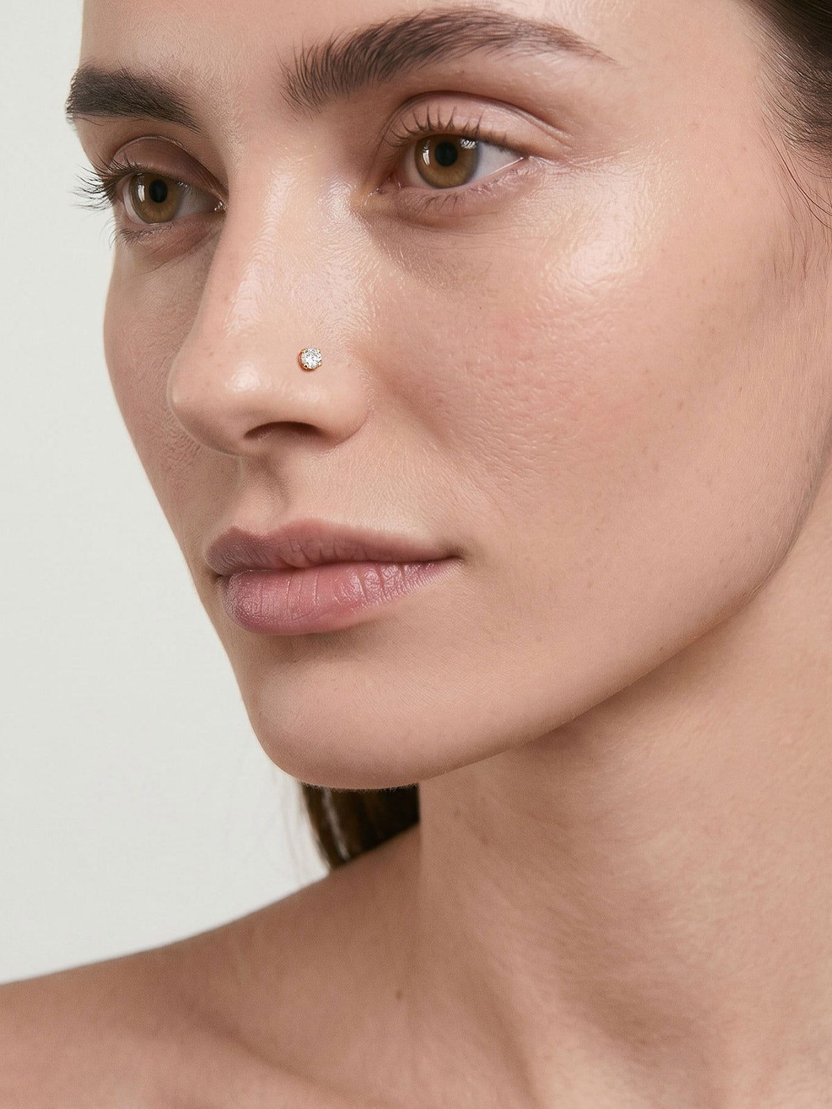 Soft natural portrait of a woman wearing tiny KOSINER L-shaped nose stud, delicate subtle nostril piercing for casual elegant facial jewelry styling