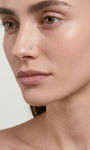 Soft natural portrait of a woman wearing tiny KOSINER twist hook nose stud, delicate subtle nostril piercing for casual elegant facial jewelry look
