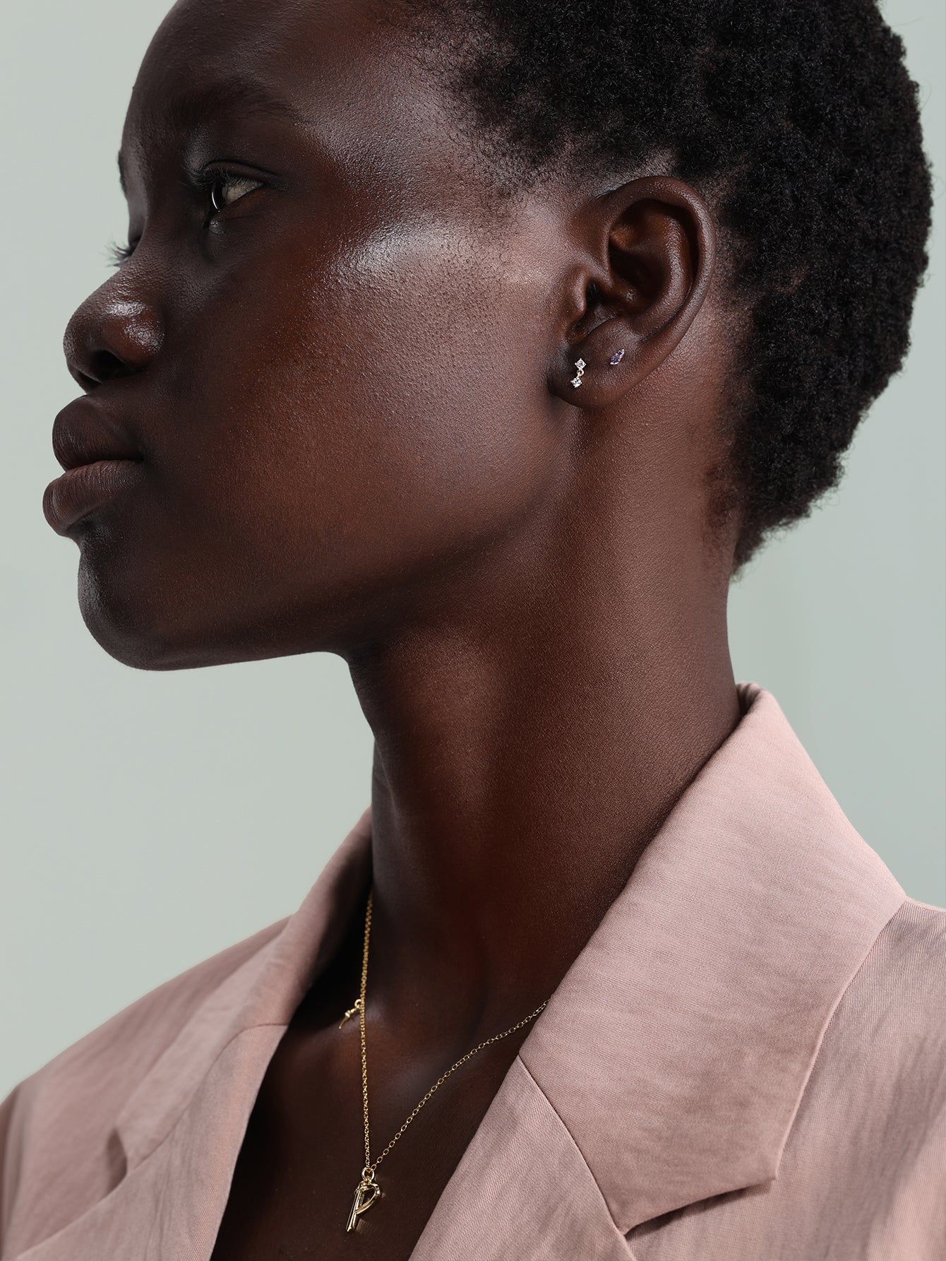 14K solid gold mini stud piercing with small cubic zirconia on a model's earlobe, flat back closure.