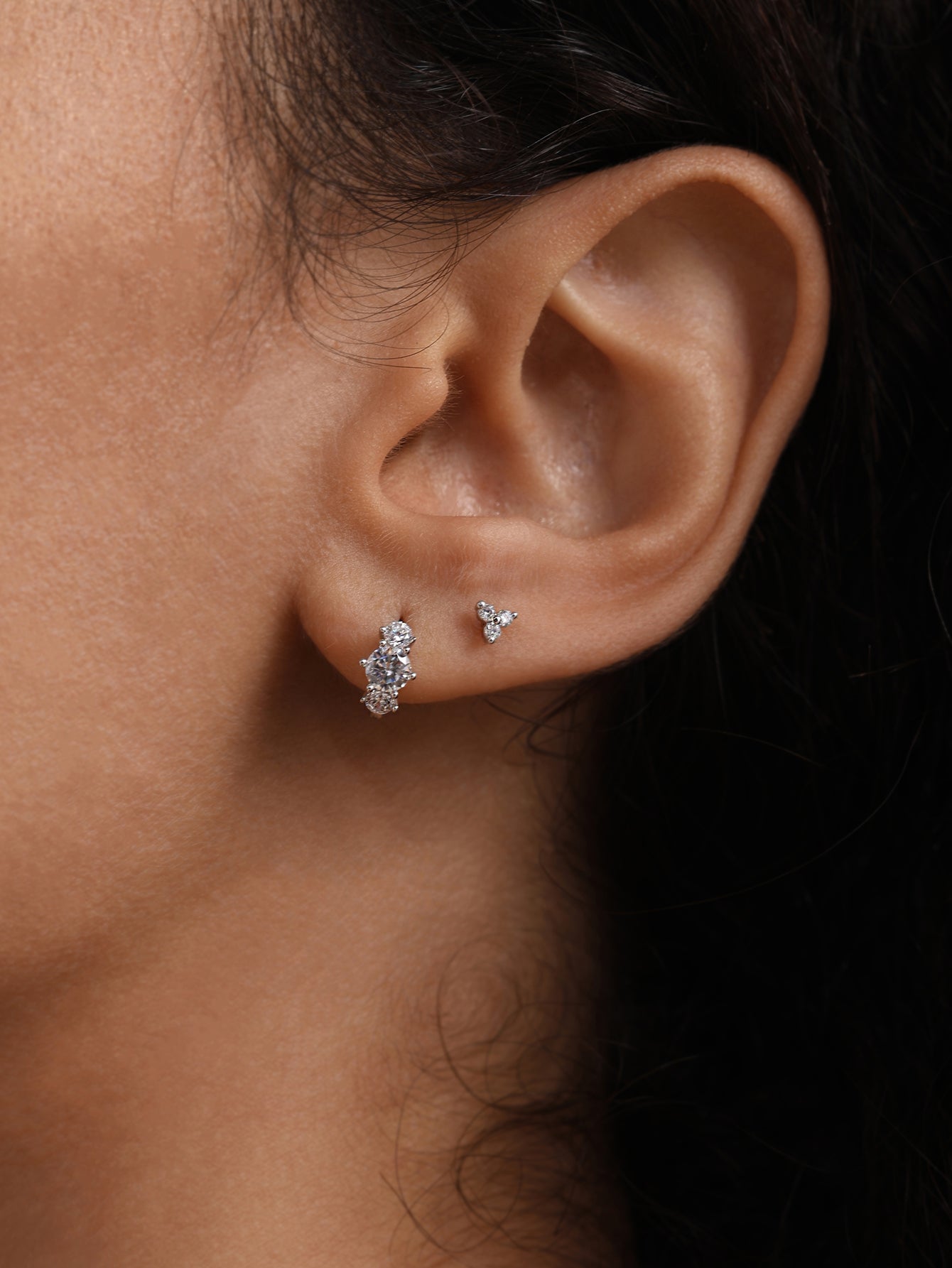 14K solid gold trinity ear piercing studs with cubic zirconia stones, shown on ear.