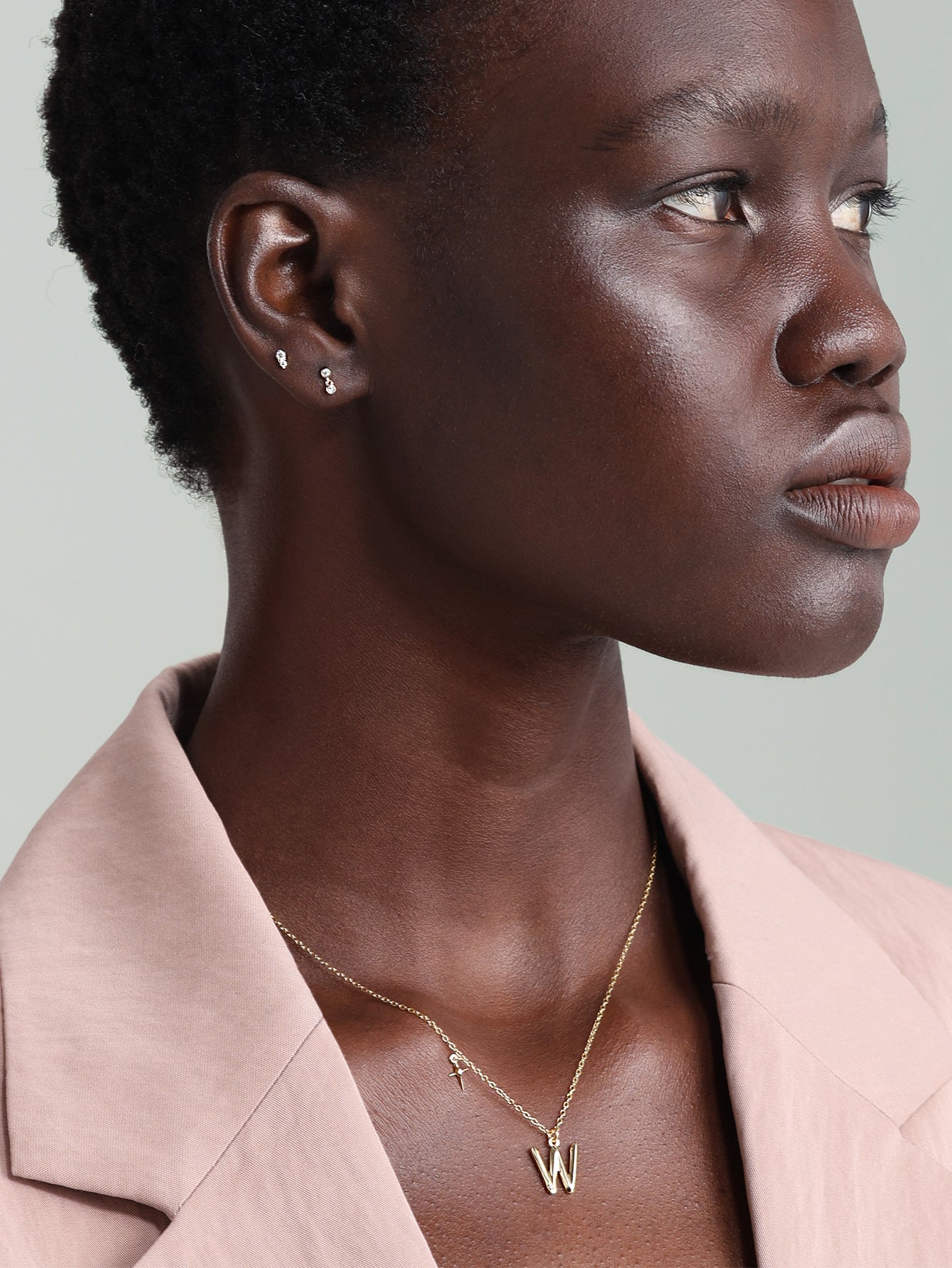 14K solid gold ear piercing stud with two clear stones vertically aligned, shown on model.