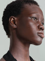 Model wearing two 14K solid gold labret studs on ear: one with a round cubic zirconia, the other with a leaf design.