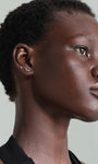 Model wearing two 14K solid gold labret studs on ear: one with a round cubic zirconia, the other with a leaf design.