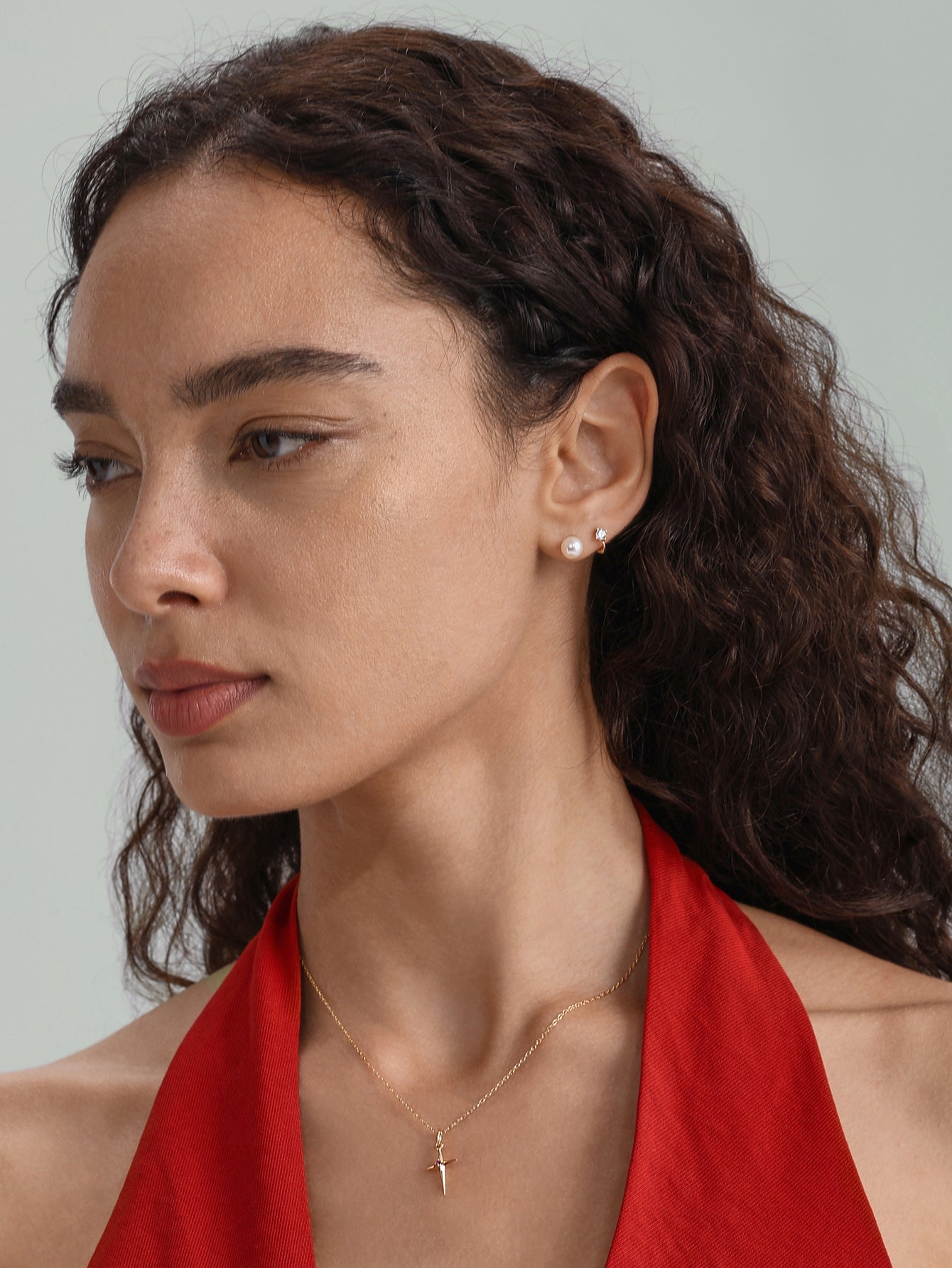 14K solid gold 6mm mini huggie hoop with cubic zirconia shown on earlobe next to a pearl stud.