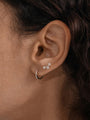 Model wearing 14K solid gold huggie earring with cubic zirconia, paired with star stud earrings.