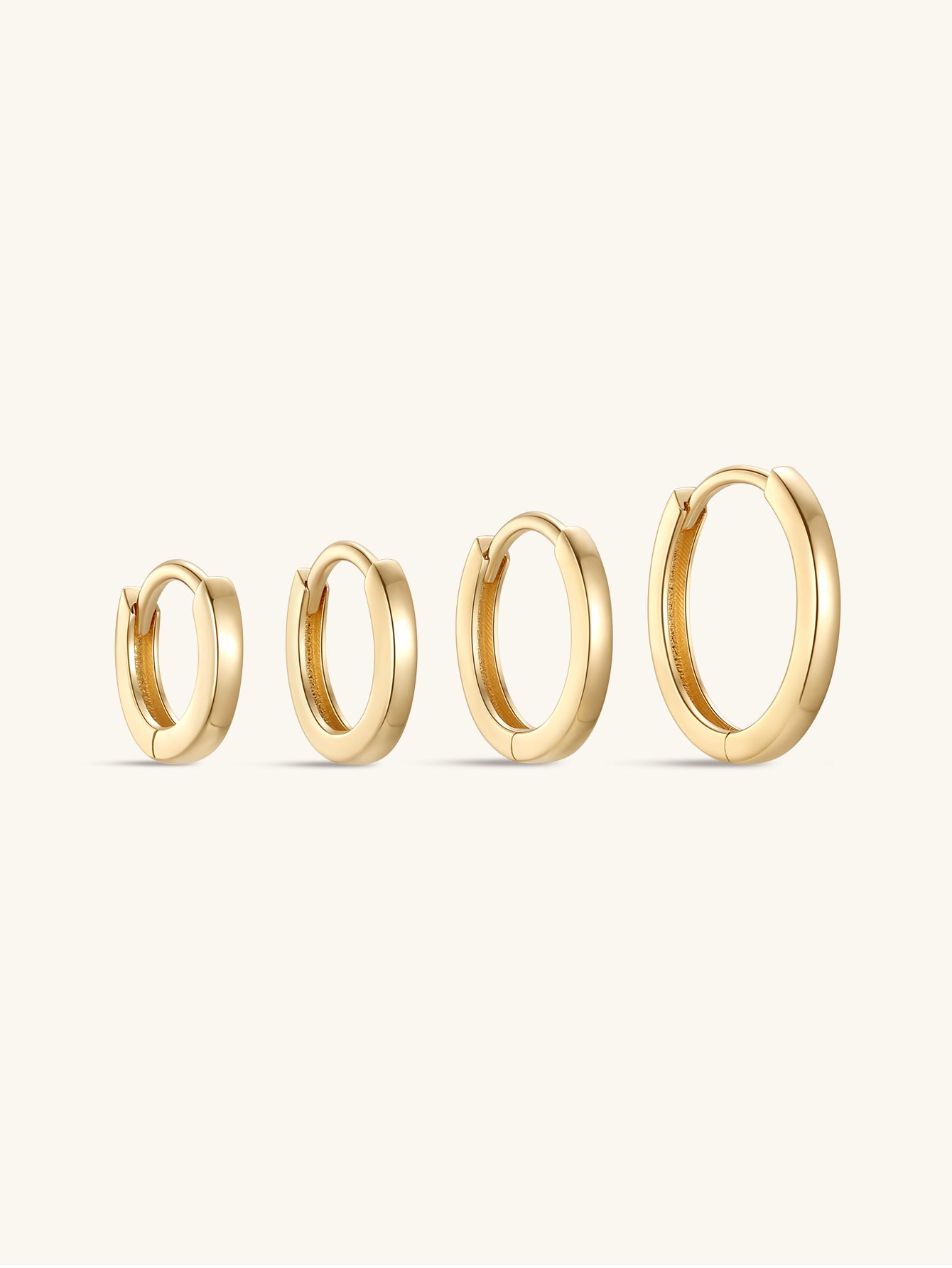 Four glossy solid 14K gold hoop earrings in various sizes, product view.
