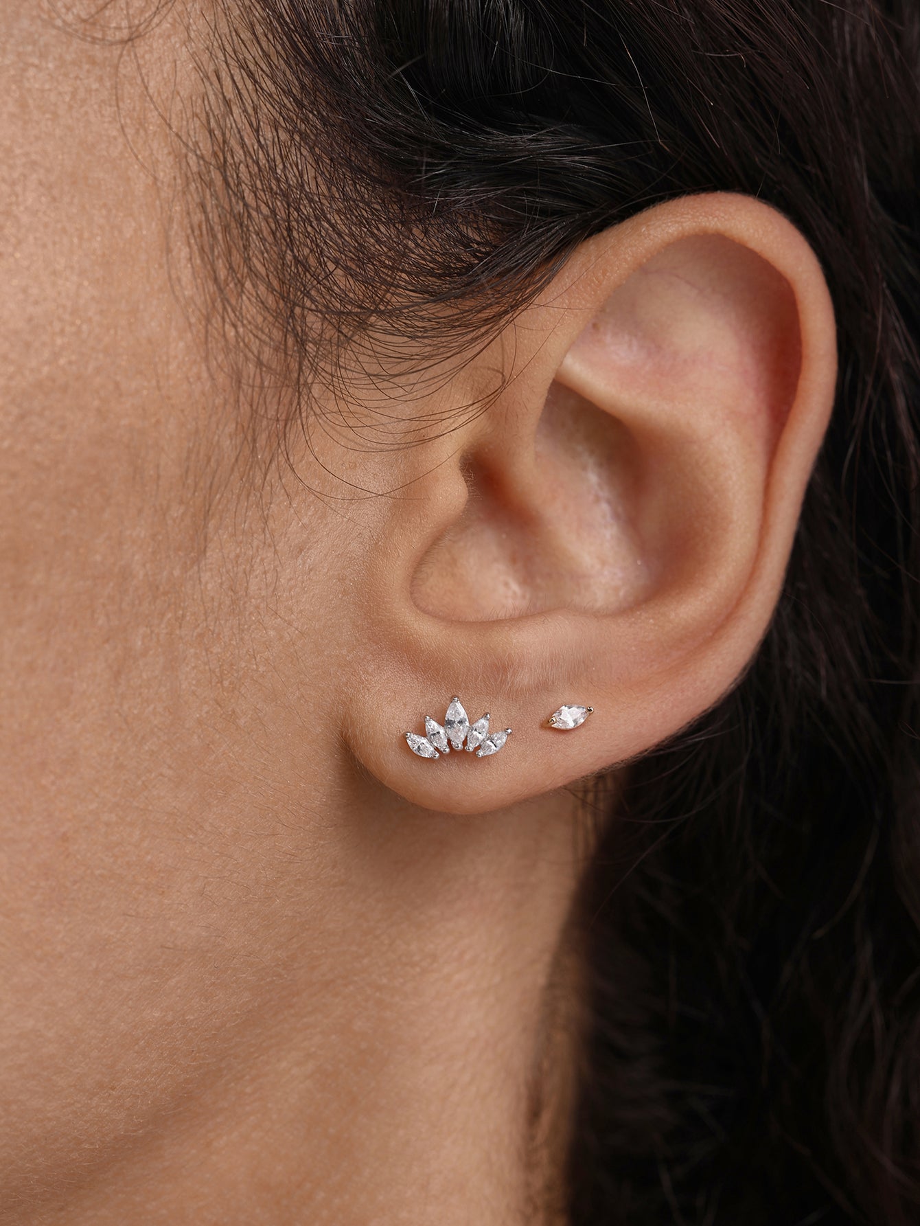 14K solid gold crown stud earrings with marquise cubic zirconia, shown on ear lobe.