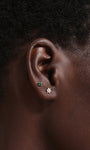 14K solid gold Bloom ear piercing studs with green and starburst cubic zirconia designs on ear.