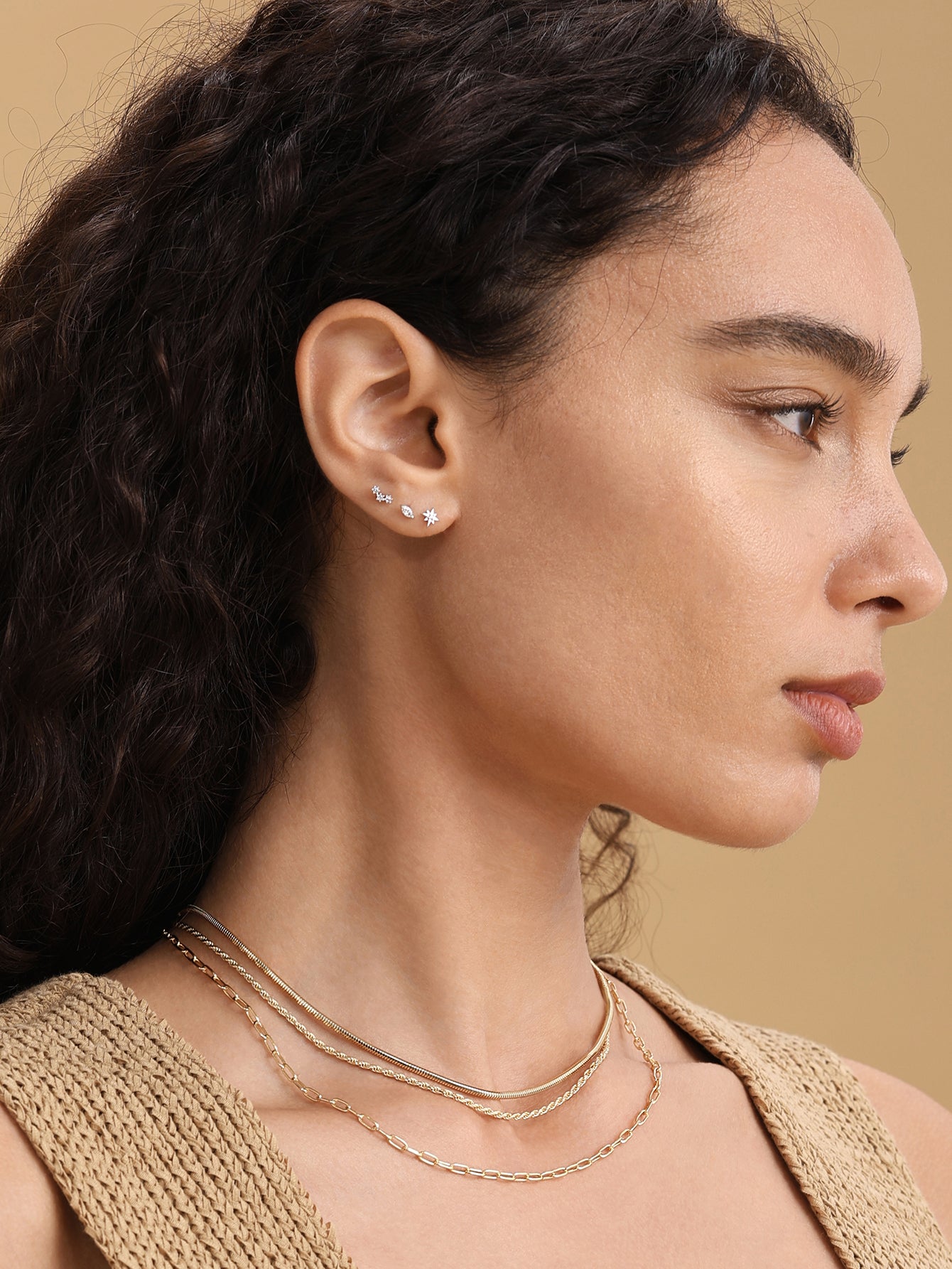 Model wearing 14K solid gold ear piercing stud with starburst design and cubic zirconia center.