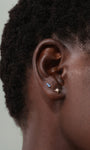 14K massief gouden starburst stud met CZ midden op het oor, gecombineerd met blauwe stenen stud.