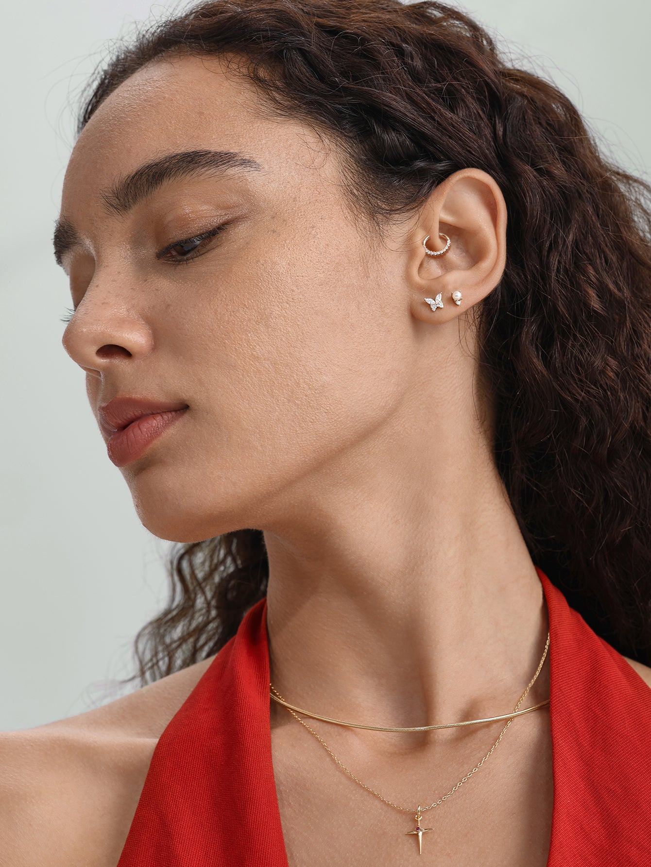 14K solid gold 18g hoop earring with prong-set cubic zirconia, model styling on ear with other jewelry.